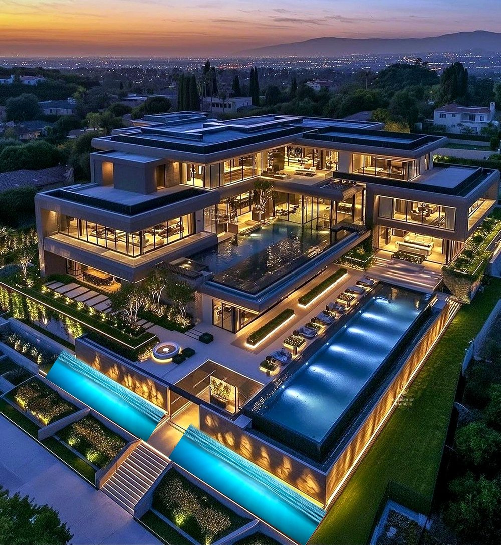 Aerial view of the terraced pools and illuminated glass facade at dusk